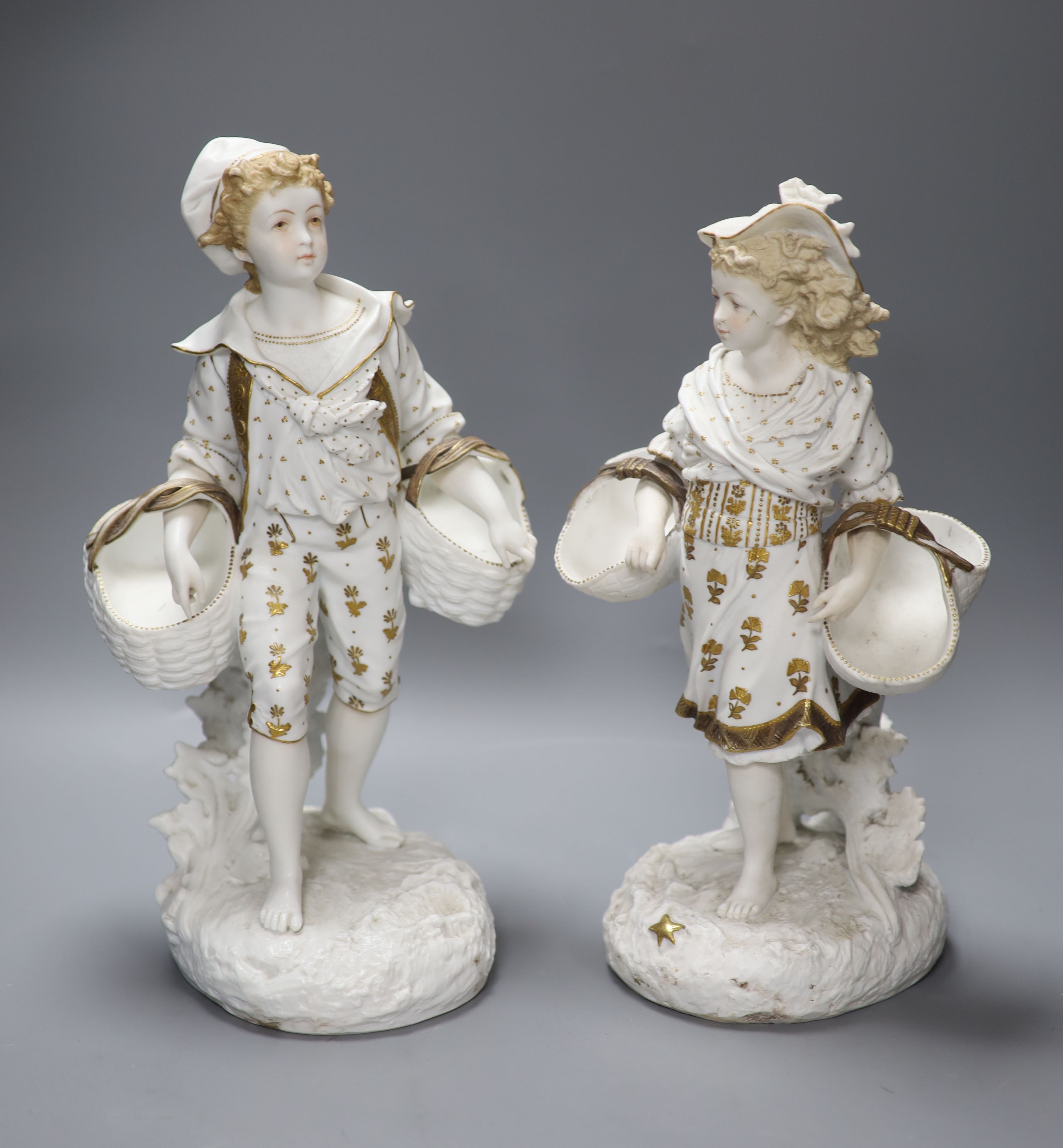 A pair of 19th century bisque gilt painted and decorated figures of a peasant boy and girl carrying baskets, 36cm